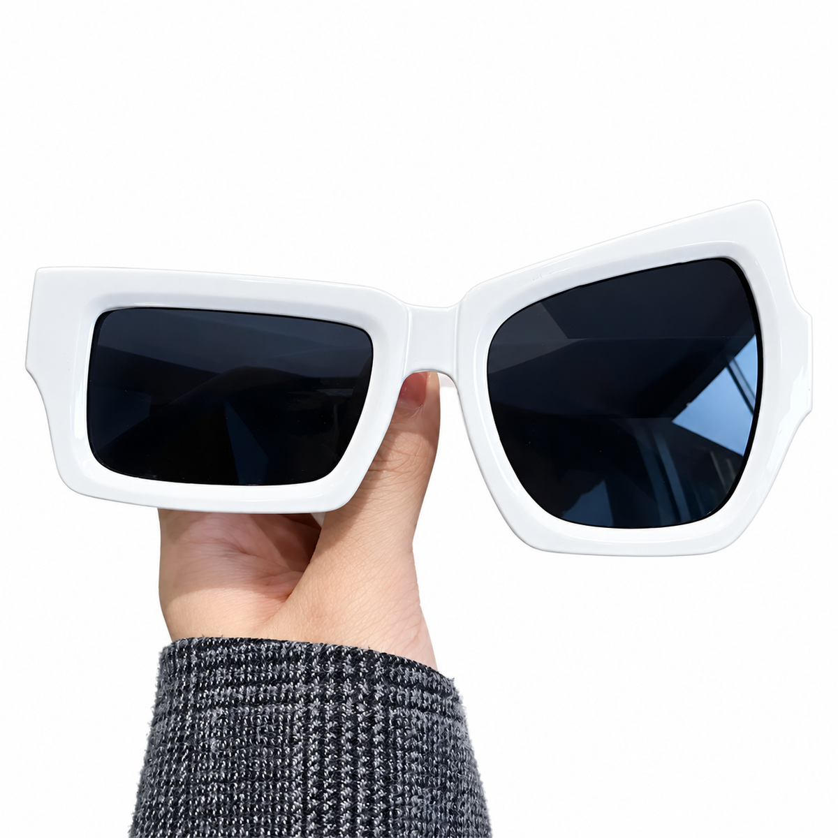 Lunettes fantaisie asymétriques blanches présentées à la main.
