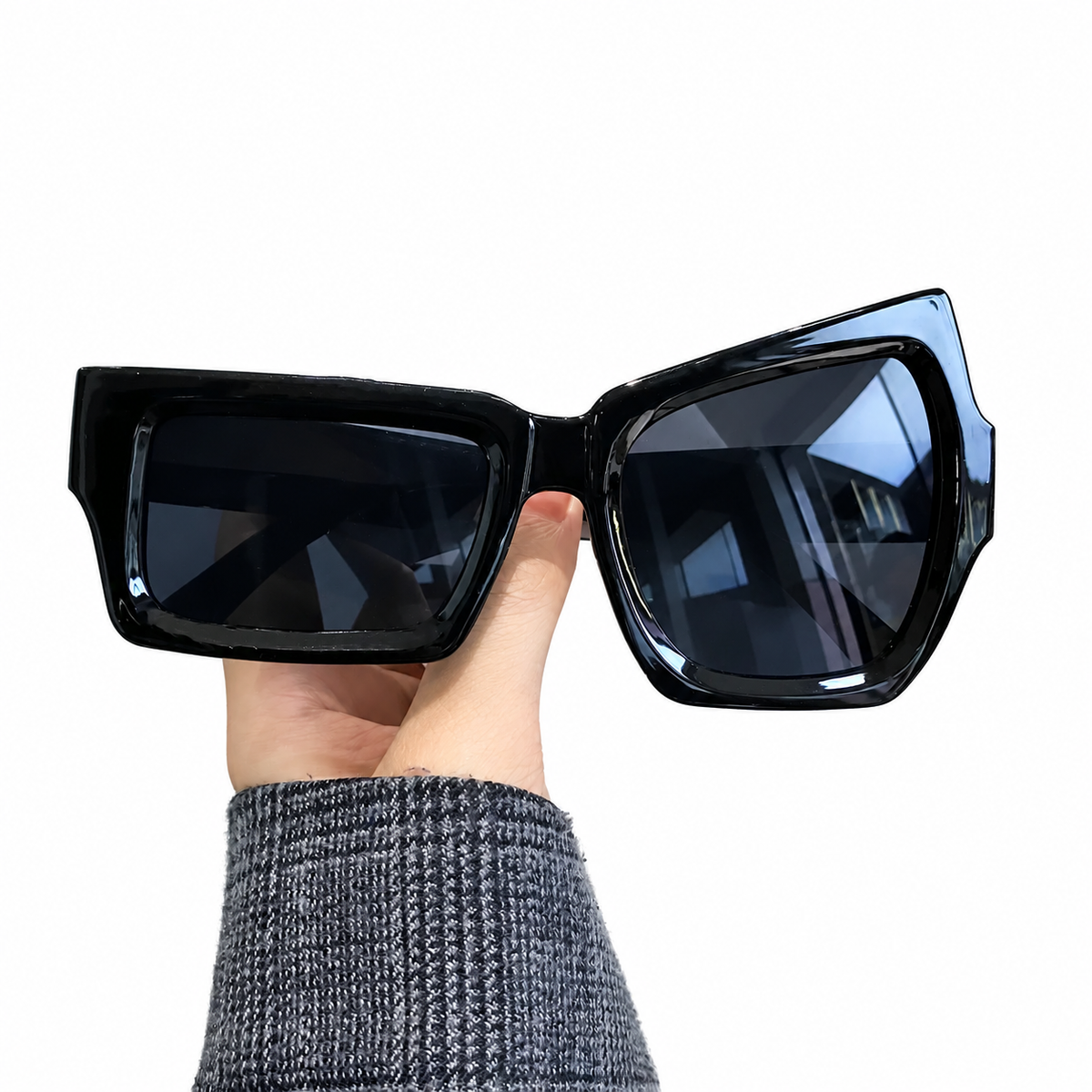 Lunettes fantaisie asymétriques noires présentées à la main, vue détaillée.